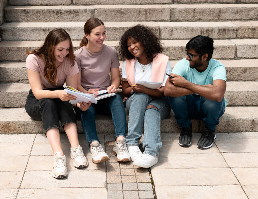 Group of students sitting on outdoor steps studying and sharing notes.