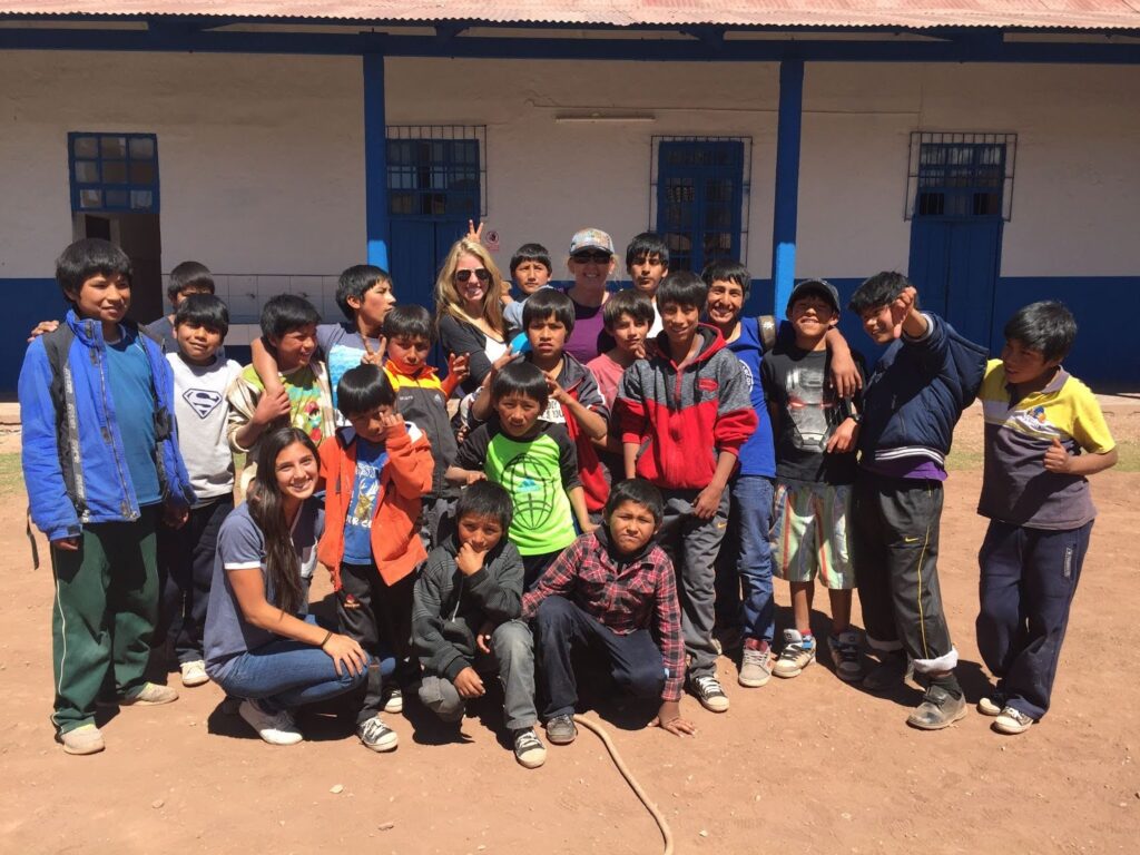 Group of children and adults posing together outside a school building.