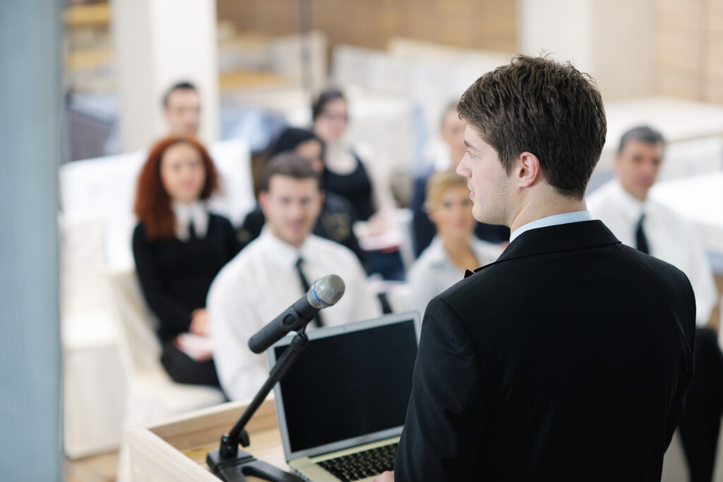 Student speaking at a podium in front of an audience.