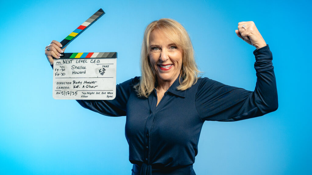 Woman celebrating while holding a film clapperboard against a blue background.