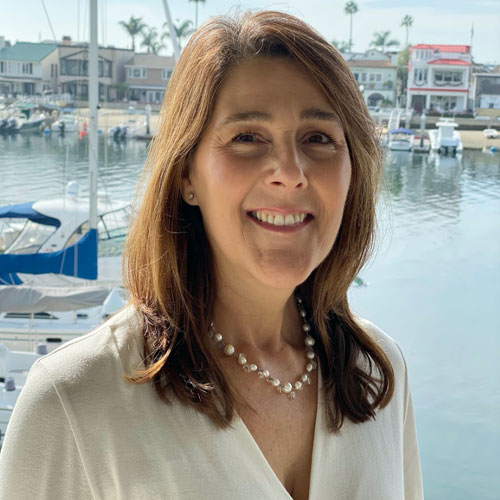 Woman smiling in front of a waterfront marina.