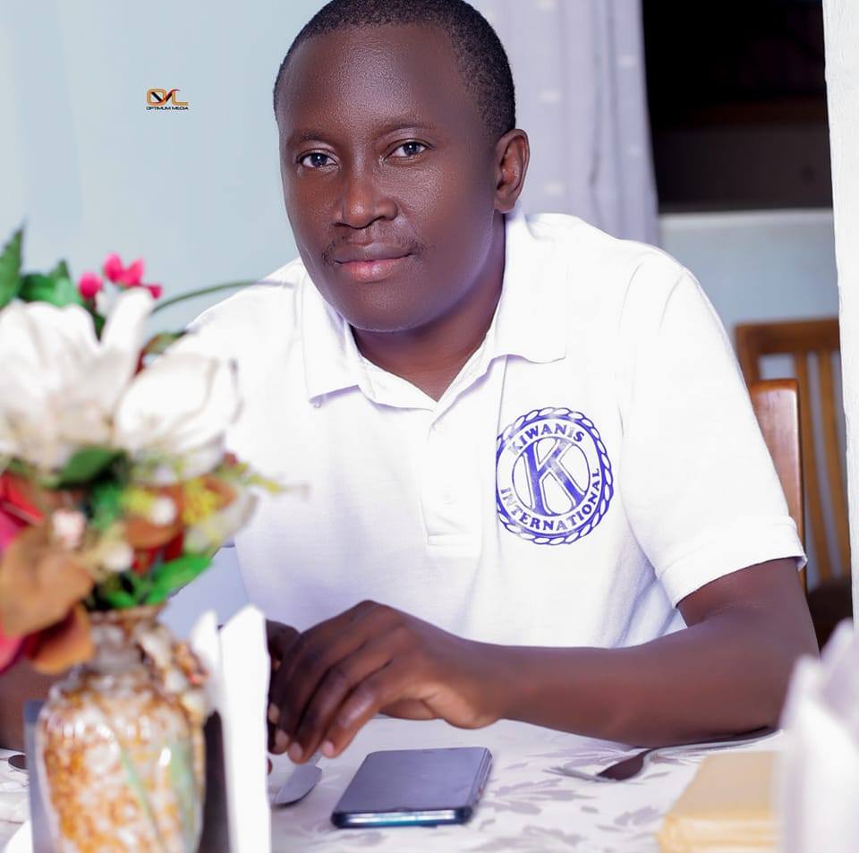 Student in a school uniform sitting at a desk with flowers and a notebook.