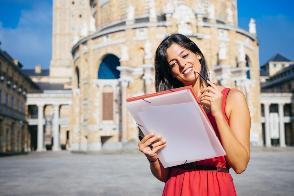 Female college student reading documents outside a European university.