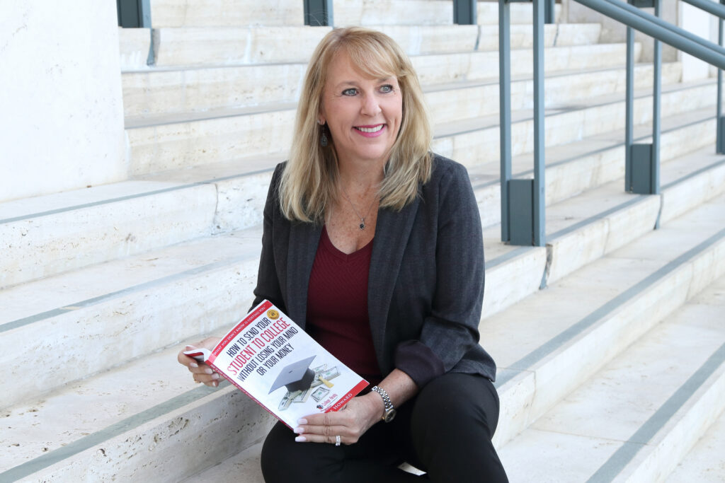 College admissions consultant holding educational planning book while seated on staircase.