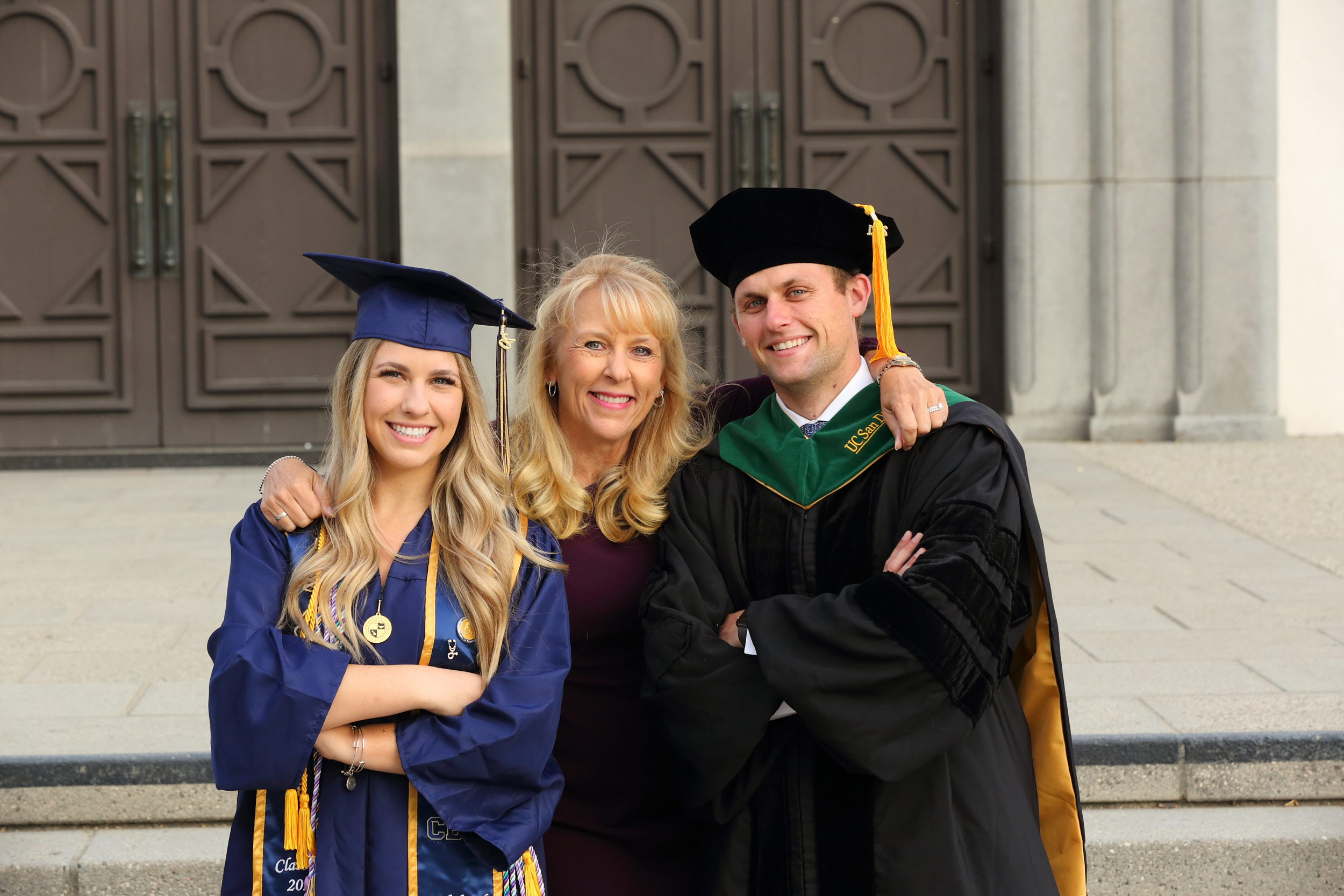 College graduates in caps and gowns posing together outside a university building.