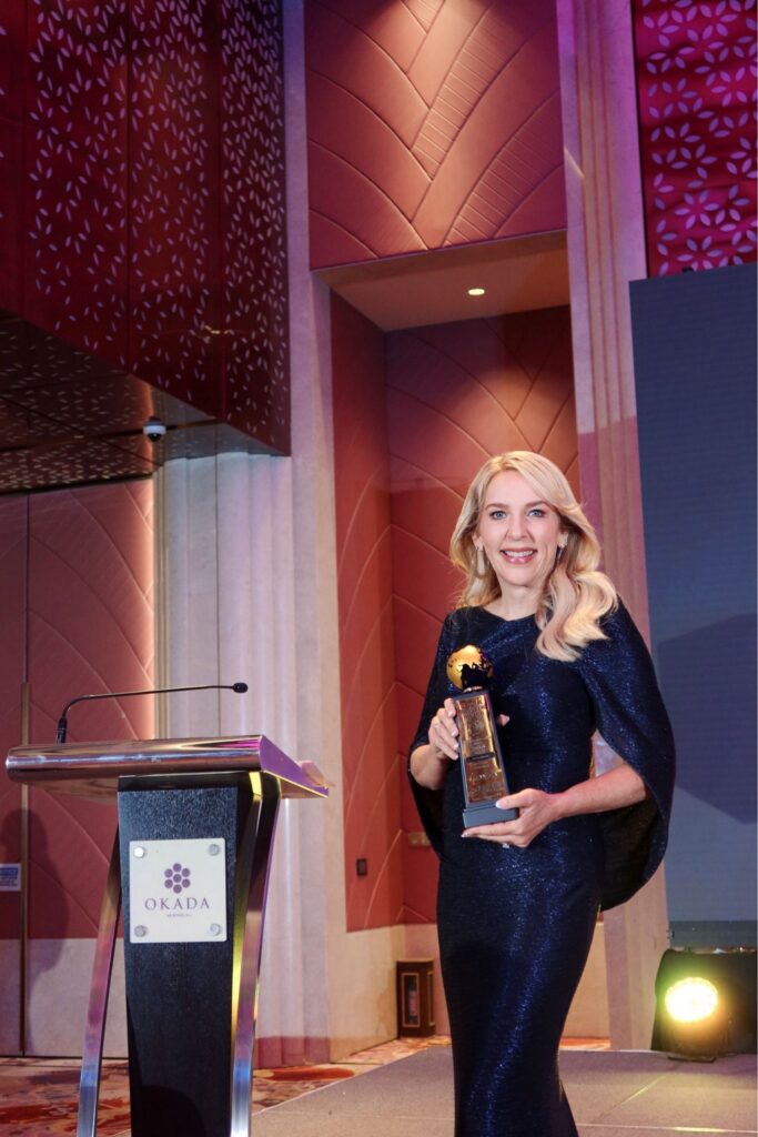 Education consultant holding award on stage at university admissions conference.
