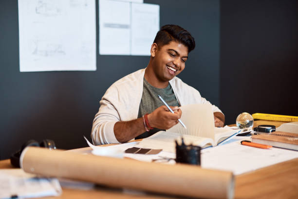 Shot of a young architect writing in a notebook at his desk in a modern office