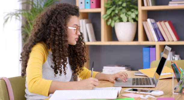 Shot of teenage girl using a laptop while doing her school work