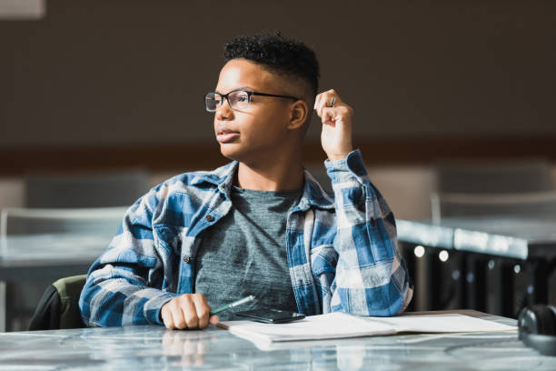The young man listens to a group of peers nearby.