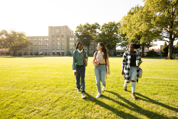 Female friends walking on university campus lawn at sunset
