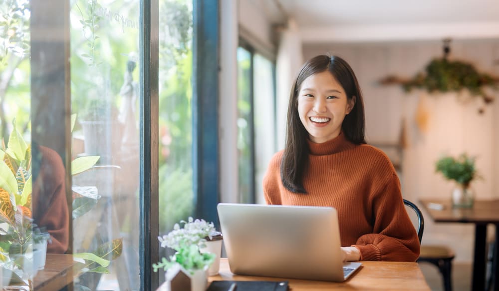 Student using a laptop at home while studying in a bright and comfortable workspace.